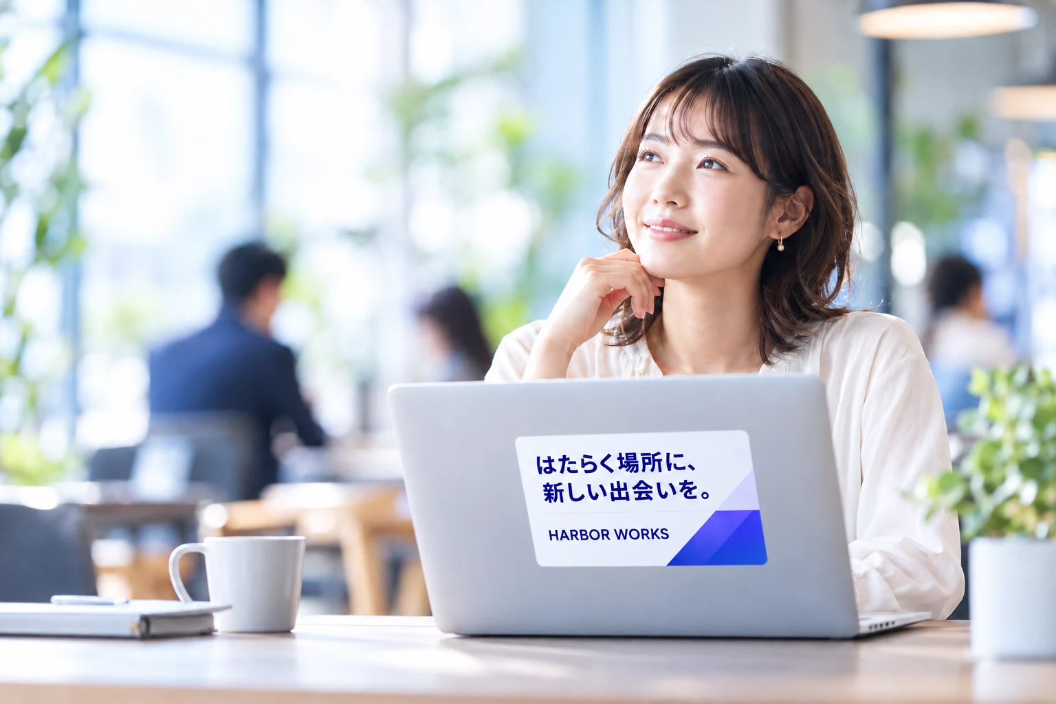 明るいカフェで架空の企業広告を貼ったノートPCを使う女性のイメージ